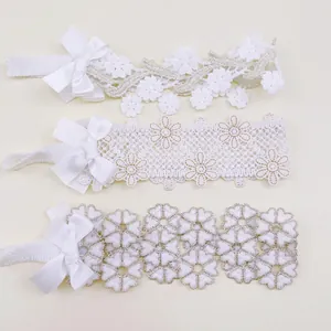 Close-up of three styles of white lace baby headbands with floral patterns and elegant satin bows