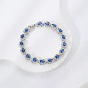 Dettaglio ravvicinato di un elegante bracciale in argento con zirconi blu a goccia