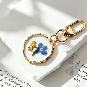 Detail van een handgemaakte hars sleutelhanger met echte blauwe gedroogde bloem en goudvis