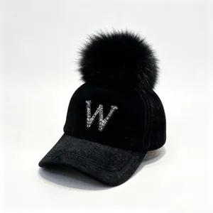 Detail view of stylish black velvet cap featuring a sparkling rhinestone letter W design