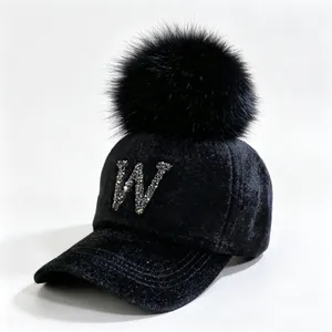 Close-up of black faux mink baseball cap with rhinestone letter W and fur pom-pom.