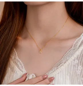 Détail d'un pendentif lettre o minuscule dorée sur une fine chaîne en argent 925