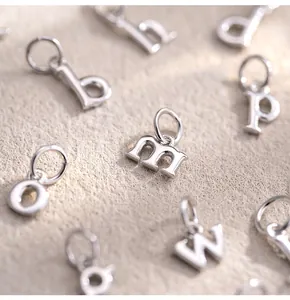 Gros plan détaillé de plusieurs pendentifs alphabet en argent sterling 925 pour DIY