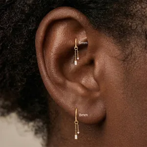 Detail of gold marquise charm hoop earrings in 6mm and 8mm sizes on a person's ear.