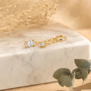 Macro view of marquise-cut crystal earring charm with delicate gold chains on marble
