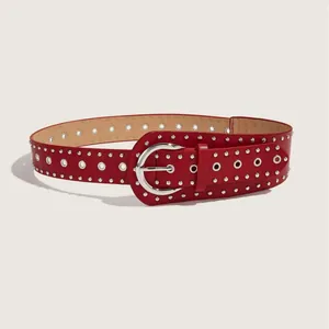 Vista dettagliata di una cintura punk in pelle rossa con rivetti argentati e occhielli metallici