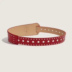 Dettaglio ravvicinato di una cintura punk rossa con borchie argentate e occhielli metallici