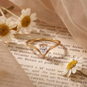 Elegant V-shaped gold ring with a pear-shaped sparkling zircon on a vintage book