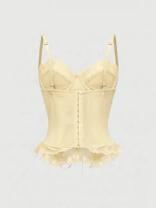 Detailed view of a pale yellow lace corset top with hook-and-eye front closure and straps.