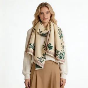 Detailed view of cream cashmere-like scarf with green magnolia print on female model