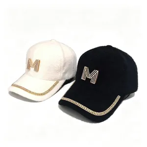 Detail view of winter mink velvet baseball caps with rhinestone M logo and chain trim.