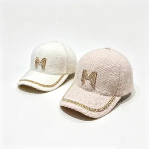 Detail view of rhinestone M logo and chain on plush faux mink fur winter baseball caps