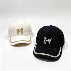 Detailed view of black and white plush baseball caps with rhinestone M logo and chain brim