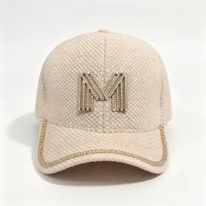 Detailed view of rhinestone M logo and sparkling chain trim on a beige mink velvet cap