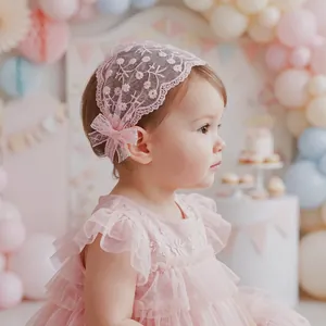 Gros plan d'un bébé portant un bandeau en dentelle rose avec broderie florale.