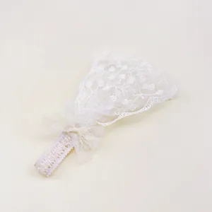 Gros plan d'un bandeau en dentelle blanche pour bébé avec broderie florale et nœud