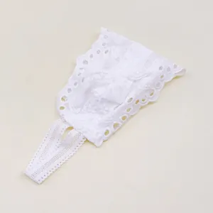 Vue détaillée d'un bandeau en dentelle blanche pour bébé avec broderies et petit nœud.