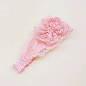 Détail d'un bandeau en dentelle rose avec une fleur pour bébés et petites filles