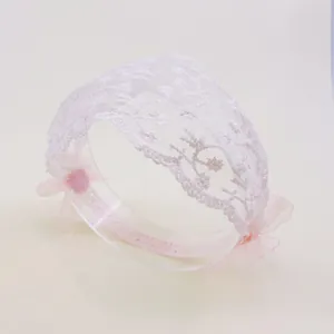 Vue détaillée d'un bandeau pour bébé en dentelle florale blanche avec nœuds roses