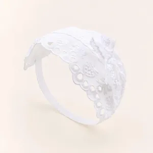 Gros plan d'un bandeau en dentelle blanche pour bébé avec nœud et motifs ajourés délicats