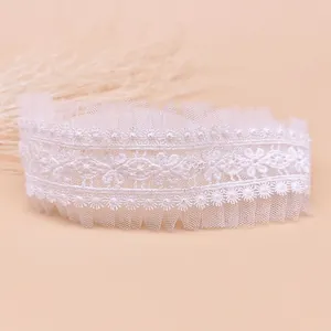 Vue détaillée du bandeau bébé en dentelle florale blanche avec bords en tulle