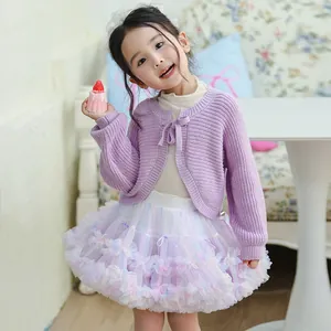 Detail view of a little girl in a purple bow knit cardigan and a pastel tutu skirt
