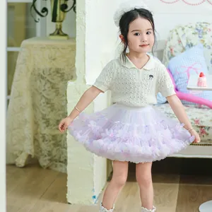 A young girl wearing a colorful pastel tiered tutu skirt with multi-layered ruffles and soft bow detail
