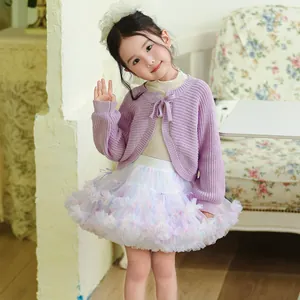 Detail of little girl wearing a purple bow cardigan and soft rainbow ruffled tutu skirt