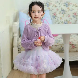 Detailed view of girl's purple knitted cardigan and pastel rainbow tutu skirt