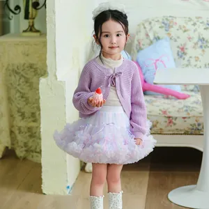 Detailed view of child's pastel tutu skirt styled with a purple knit cardigan