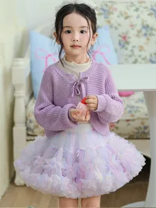 Toddler girl wearing a purple knitted cardigan and a colorful fluffy ruffled tutu cake skirt