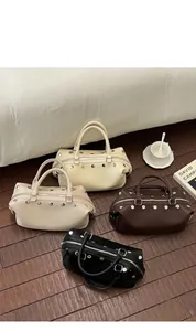 Display of four retro rivet handbags in cream, beige, brown and black on a wooden floor.