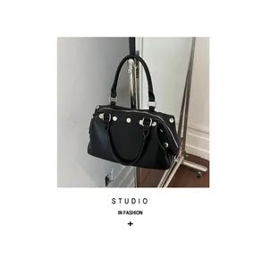 Detailed studio shot of a black retro handbag with silver rivets and metallic stand