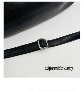 Detail view of black leather bag featuring an adjustable shoulder strap with silver buckle.