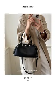 Black rivet handbag styled with a trench coat for a chic retro high-end fashion look