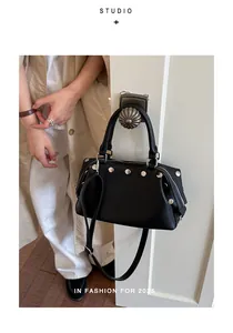 Close-up of a black retro handbag with silver rivets hanging on a vintage door