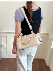 Detail view of a beige vintage rivet shoulder bag worn by a model in a casual setting.