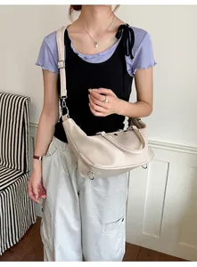 Stylish cream vintage tote bag with studs, worn as a crossbody bag by a fashion model.