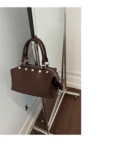 Detail shot of brown retro tote bag with silver rivet studs hanging on a rack