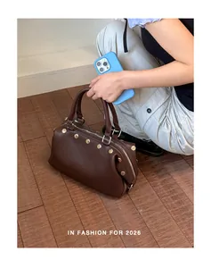 Vintage brown rivet handbag held by a model in a trendy lifestyle setting