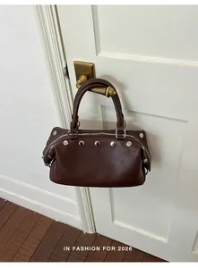 Retro brown studded handbag for women hanging on a white door handle in a stylish home setting