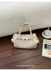 Detailed view of the stylish cream vintage riveted handbag placed on a wooden floor