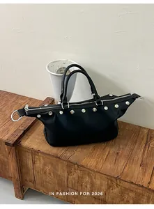 Close-up view of a stylish black rivet studded vintage tote bag resting on a rustic wooden bench