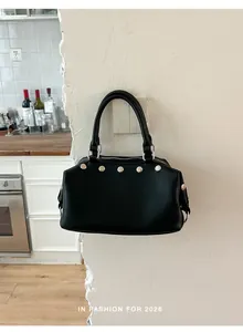 Vintage black leather tote bag with silver rivet details against a minimalist white wall