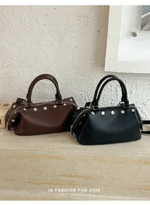 Two vintage rivet handbags in black and brown displayed on a premium marble ledge.