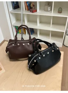 Detailed macro view of vintage rivet handbags in black and brown on a light wooden surface.