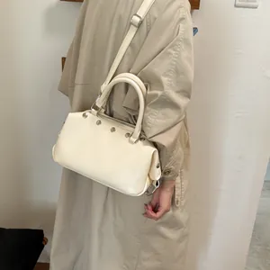 Vintage cream faux leather rivet handbag with adjustable crossbody strap shown on model