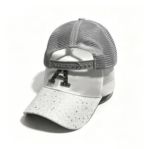 Dettaglio del cappellino trucker in mesh grigio con lettera A di strass e visiera