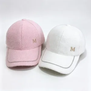 Two fuzzy mink velvet baseball caps in pink and white with rhinestone chain and M logo