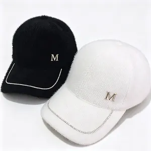 Close-up of fluffy mink velvet baseball caps with rhinestone M logo and chain trim